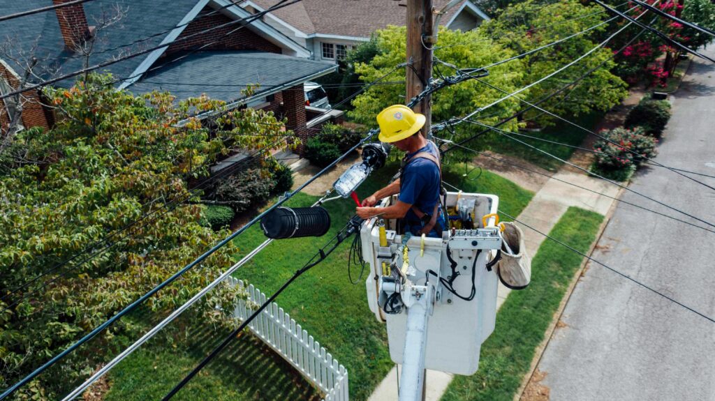 An electrician in a tower over a house.
