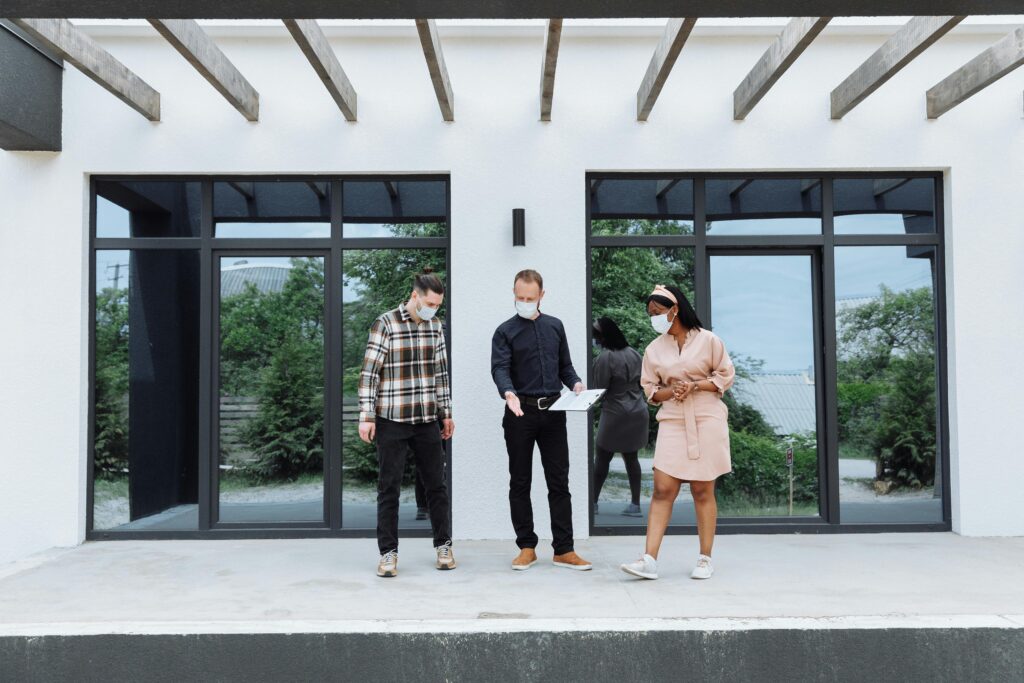 Three people standing in front of a house discussing.
